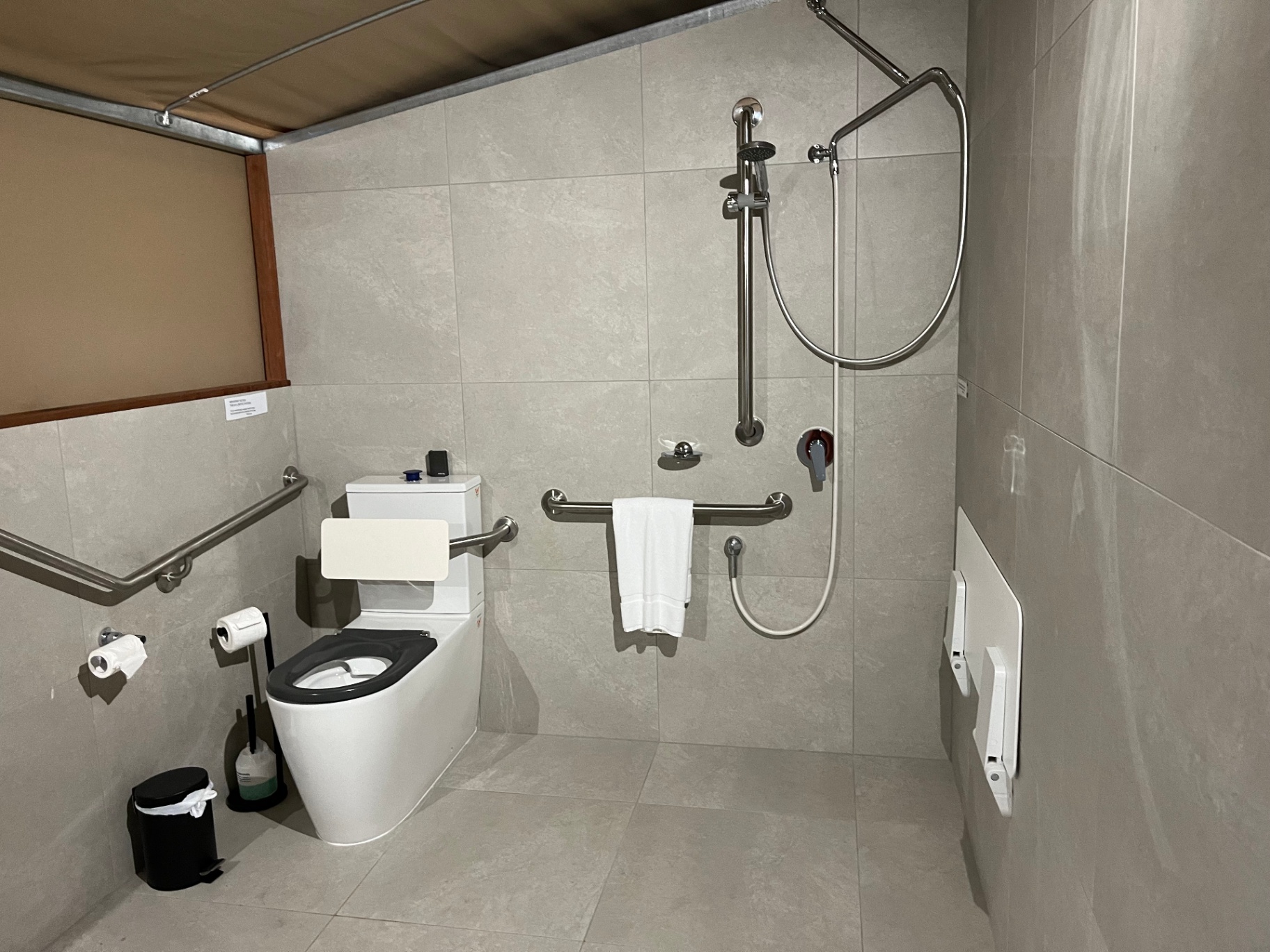 Tent 7 accessible bathroom — roll-in shower with seat, grab rails, raised toilet