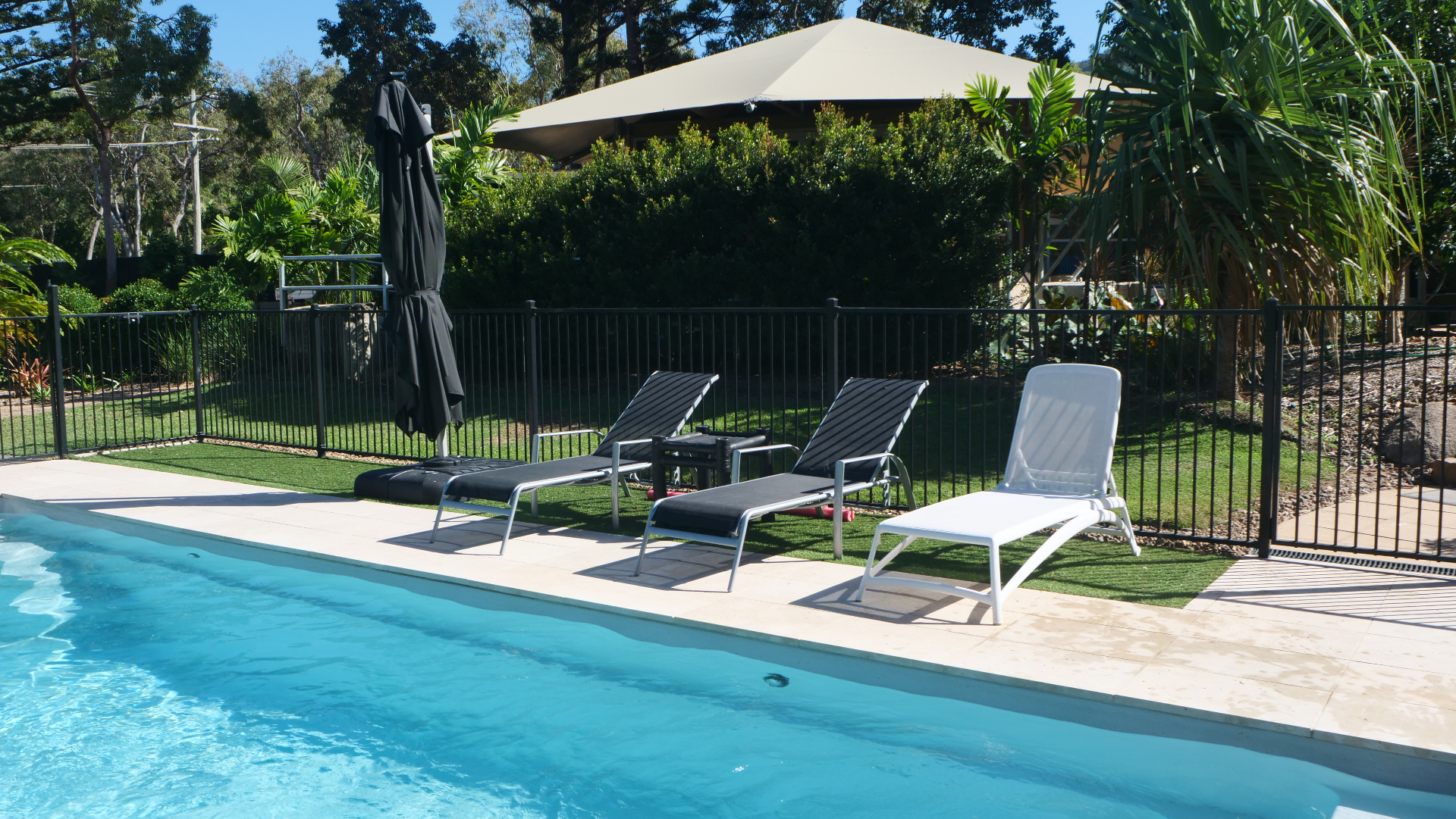 The magnesium swimming pool at Magnetic Glamping, with sun loungers and tropical garden backdrop