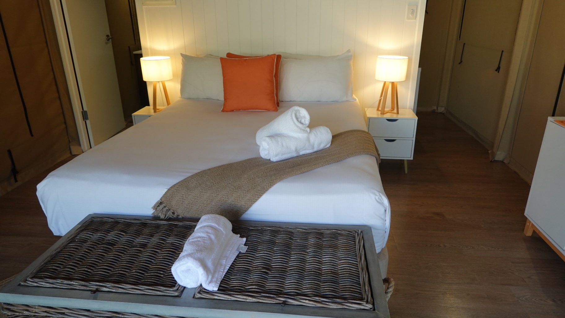King bed with warm lamp light and wicker trunk, Magnetic Glamping safari tent